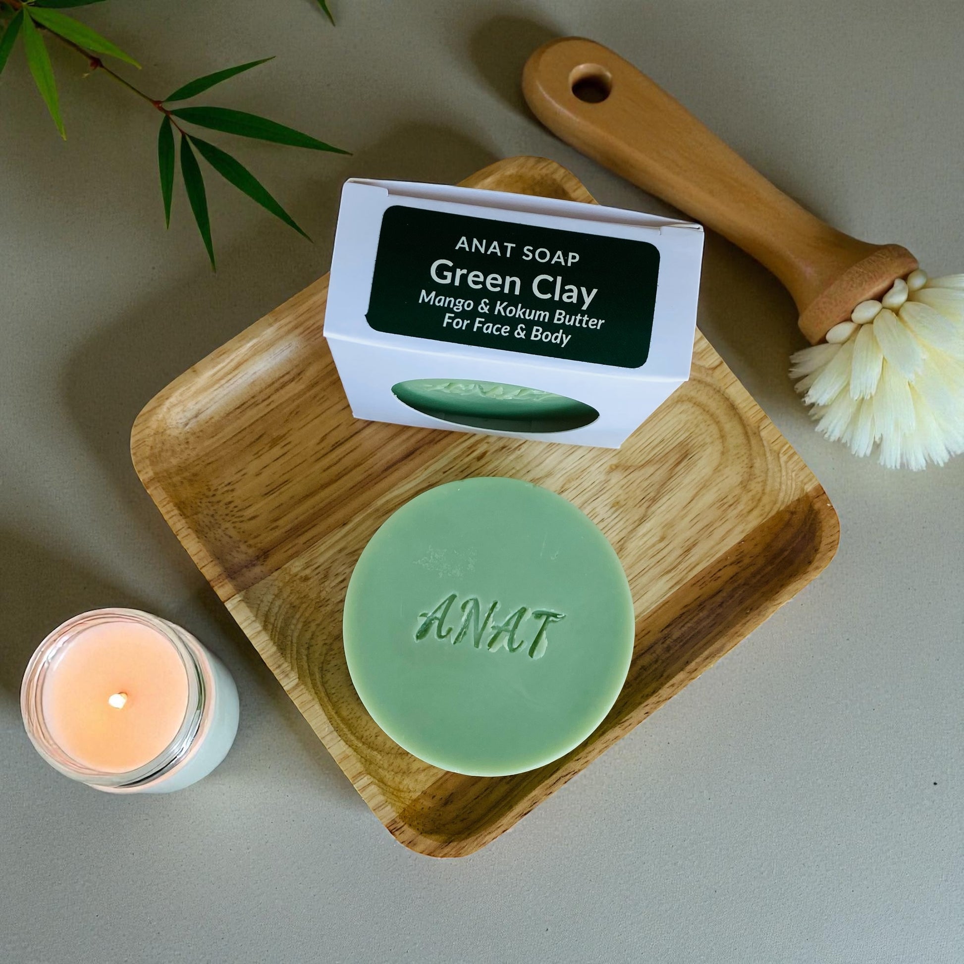 Anat Soap Green Clay round handmade plant-based soap bar with mango and kokum butters for face and body, shown on a bamboo soap dish next to the product box.